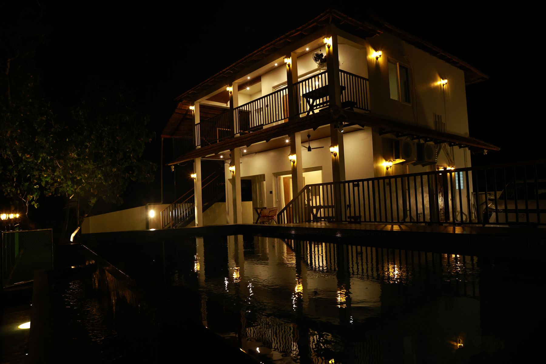 Cherai Lake Villa KAYAL lit up at night, reflected in the pool