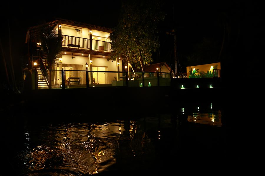 The villa lit up at night, reflected in the water